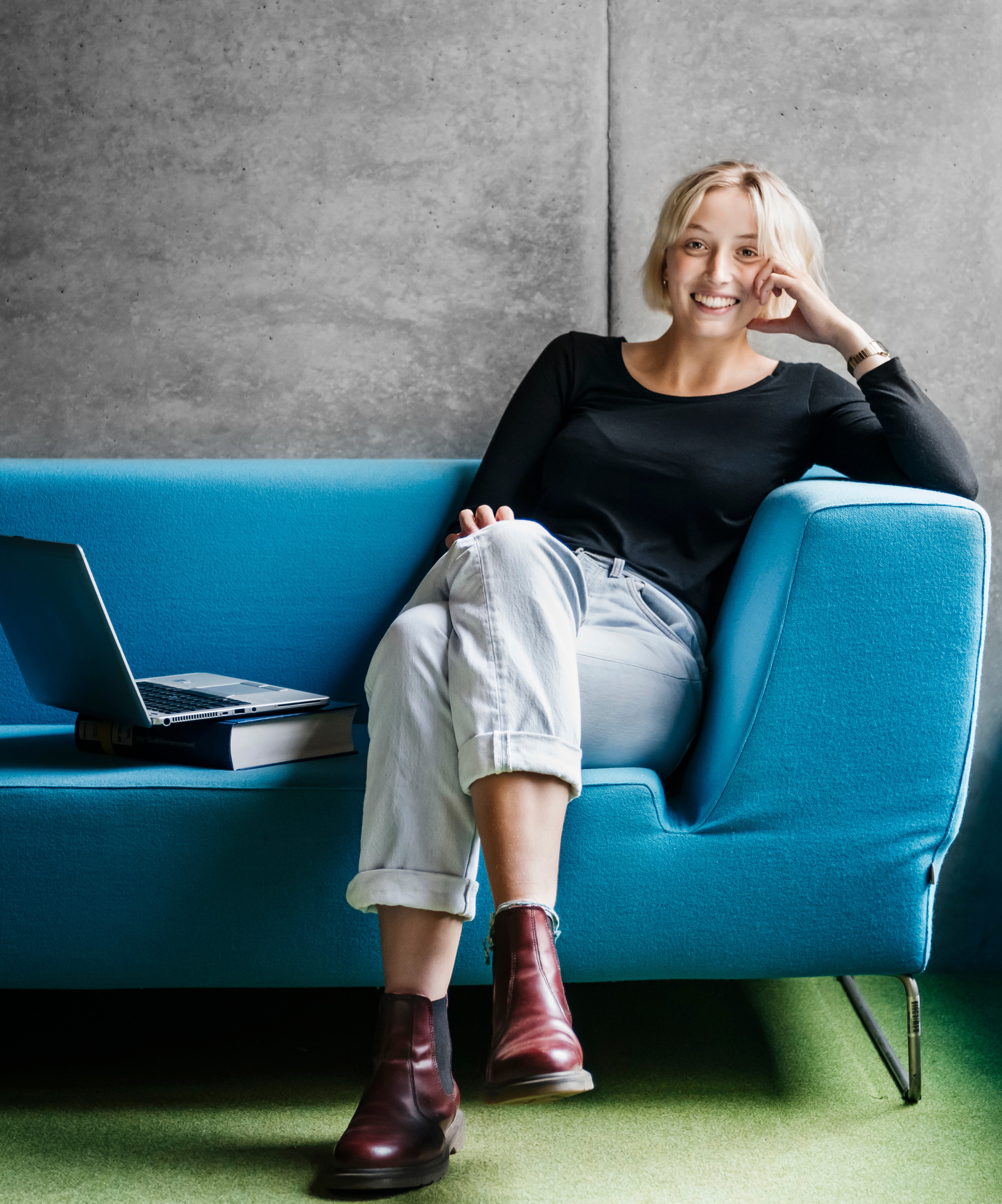 Frau sitzt lchelnd auf einem blauen Sofa